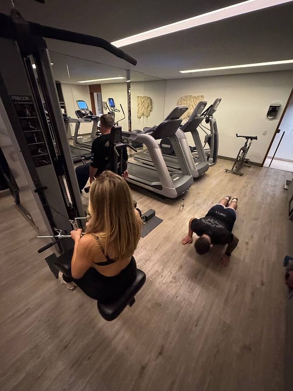 A gym scene featuring two individuals engaged in different workouts.