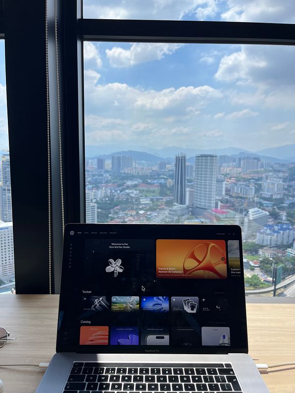 A laptop is positioned on a wooden table with a panoramic city view in the background.