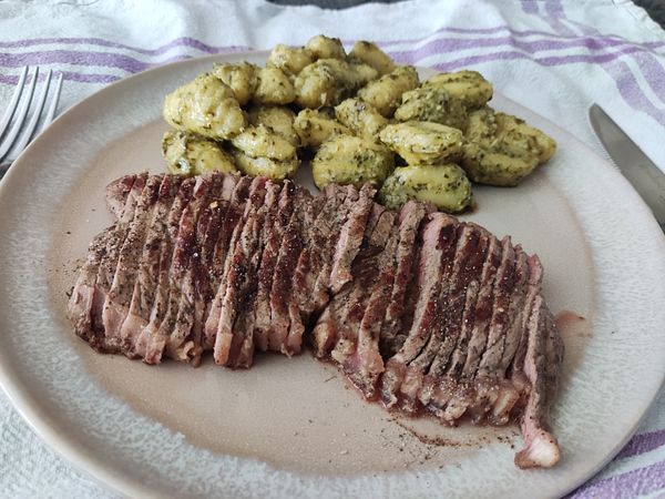 A plate featuring sliced Croatian steak alongside Italian pesto gnocchi.