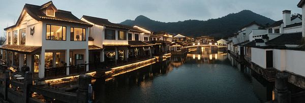 Sunset view over Xianghu Lake with silhouetted trees and hills.