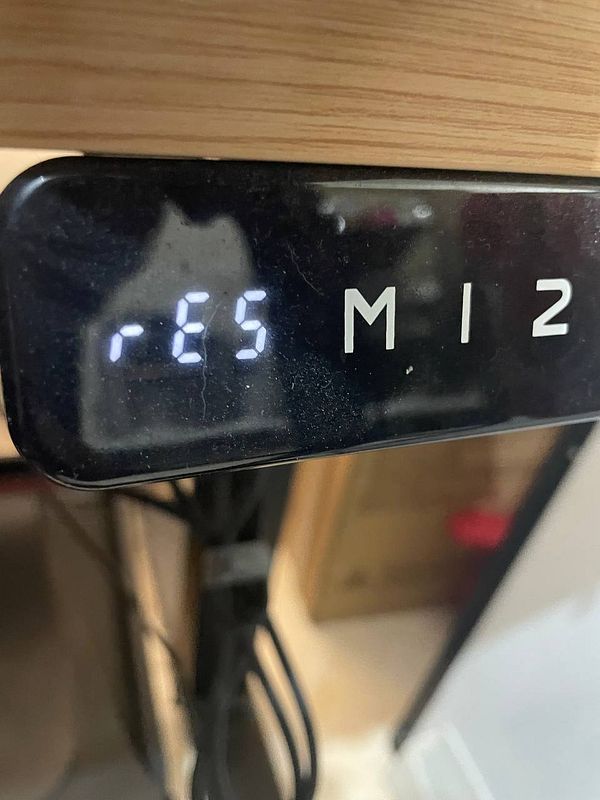 Close-up of a black standing desk control panel with buttons for height adjustment, including a digital height display showing 29.2.