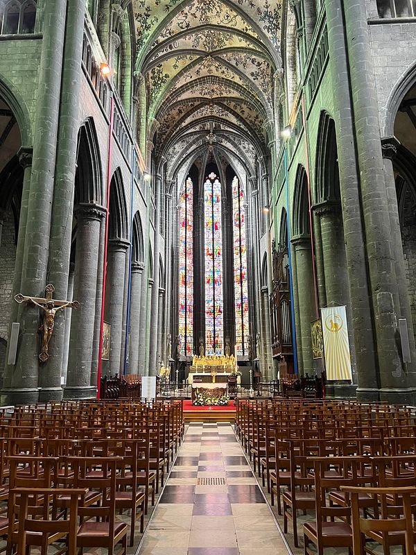 The image captures the interior of a grand cathedral featuring intricate architecture and colorful stained glass windows.
