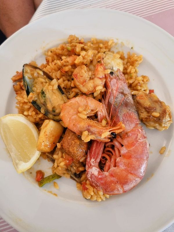 A vibrant plate of seafood paella garnished with lemon slices.