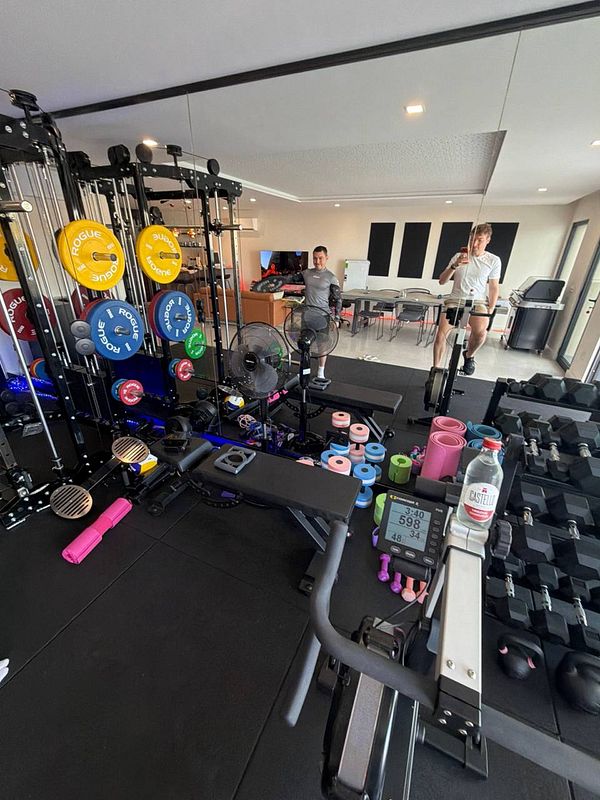A well-equipped home gym featuring various workout equipment and two individuals preparing for a workout.