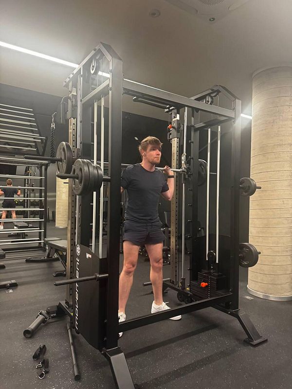 A person is performing a squat exercise using a squat rack in a gym.