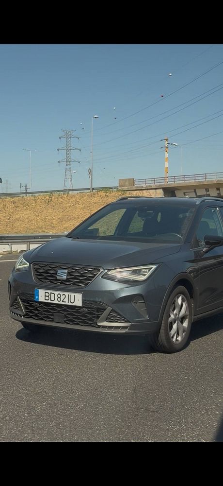 A dark gray SEAT SUV driving on a highway near an overpass with a Portuguese license plate BD 821U.