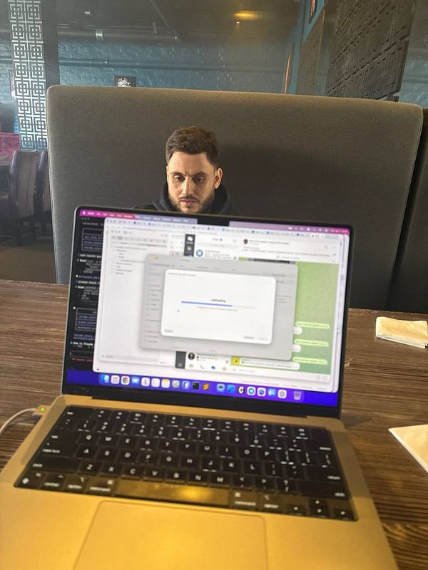 A customer support workspace with a laptop, notepad, pen, and coffee cup on a wooden table.