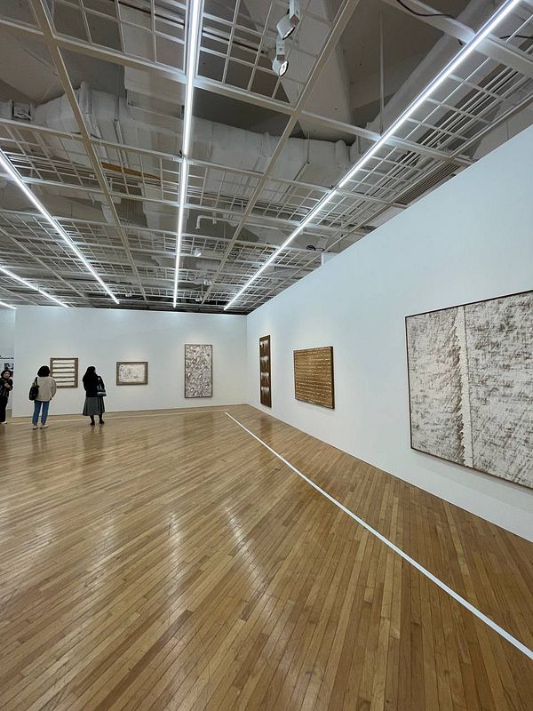 The image captures an art gallery featuring several abstract artworks and visitors exploring the space.