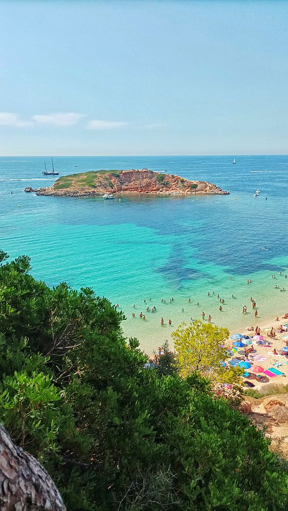 A picturesque beach scene featuring clear turquoise waters and a small island in the distance.