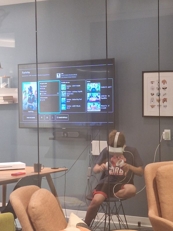 A child is playing Fortnite in virtual reality while seated in a modern room.