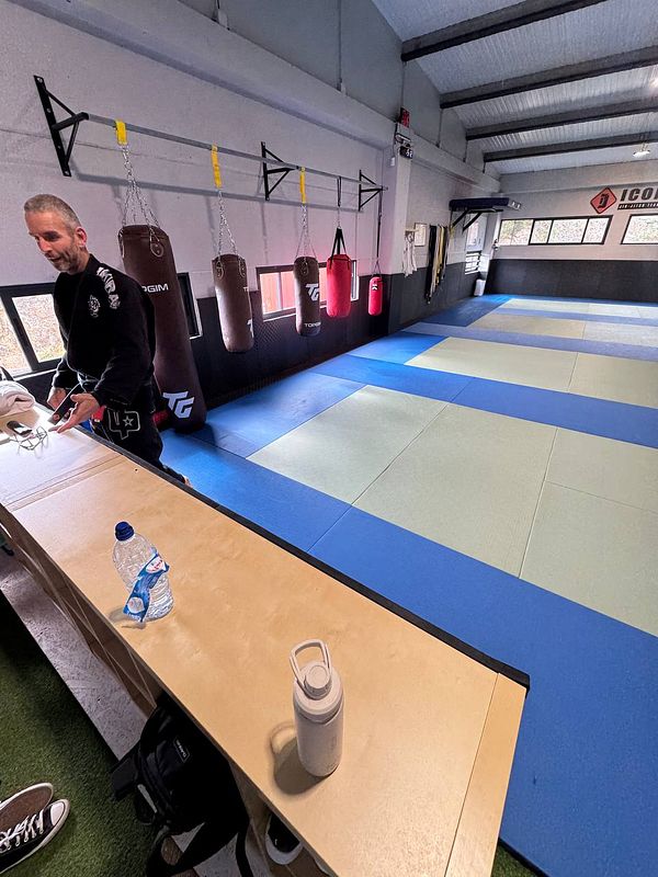 A Brazilian Jiu-Jitsu training facility with a practitioner preparing for a session.