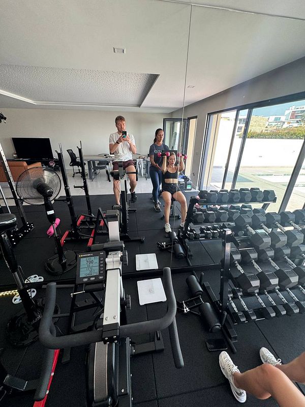 A group of three individuals is engaged in a workout session in a modern gym setting.