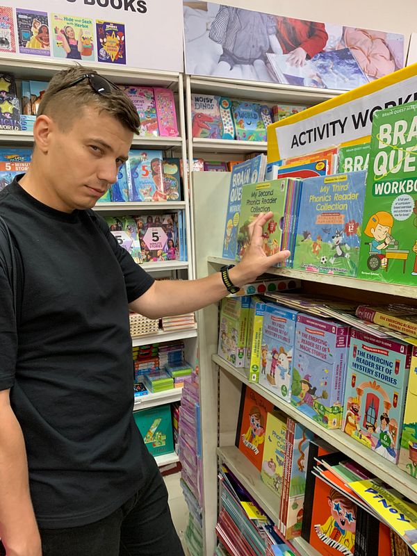 A stack of four children's books with colorful covers, lying on a couch with a floral pattern.
