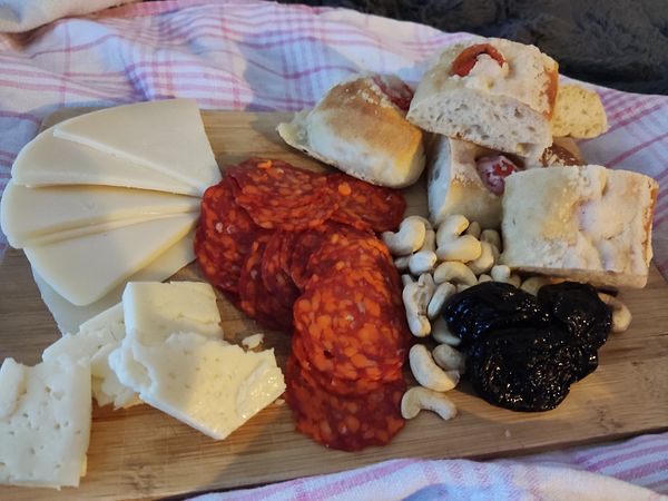A beautifully arranged Croatian brunch platter featuring various cheeses, meats, nuts, and bread.