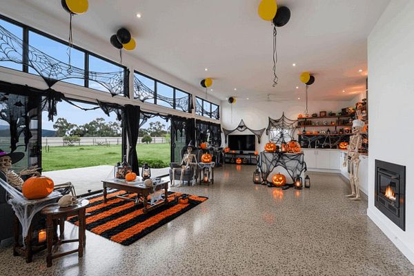 A festive Halloween-themed living room decorated with skeletons, pumpkins, and spider webs.