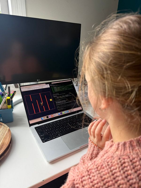 A man and a young girl stand in a warmly lit kitchen, facing each other with smiling expressions, suggesting a close relationship.