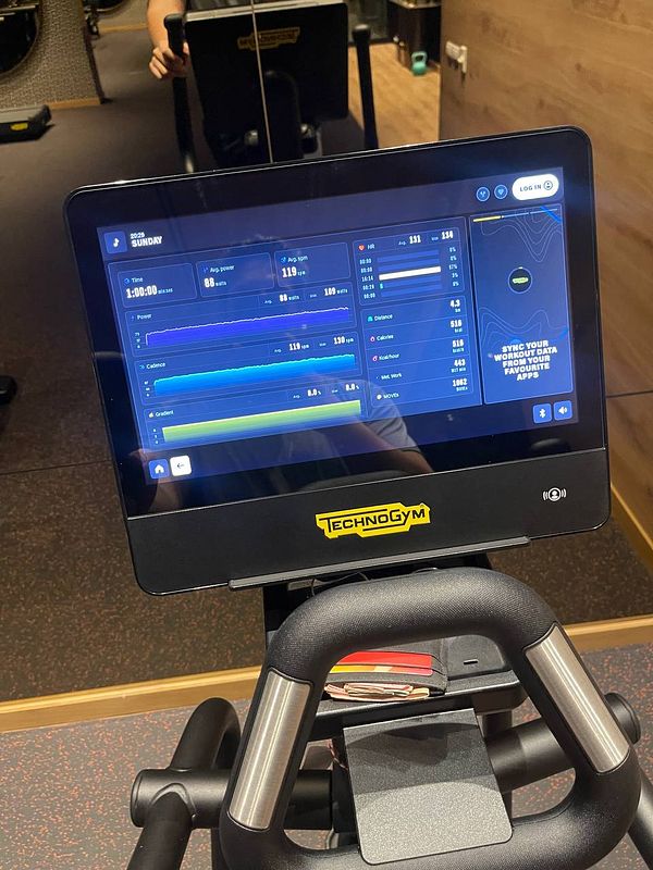 A fitness machine display shows workout metrics and options for syncing data.