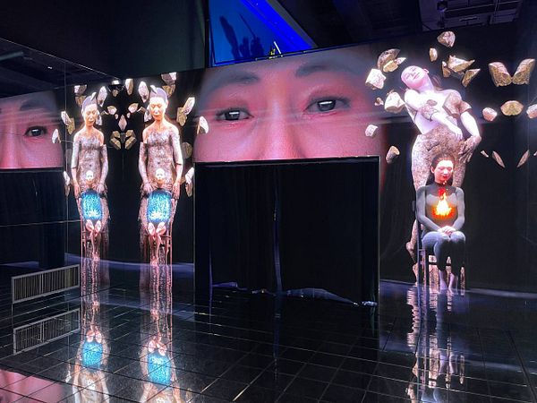 The image features a striking art installation with digital projections and reflective surfaces.