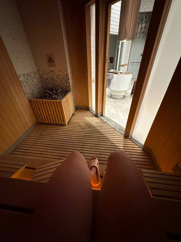 The image captures a serene sauna environment with a view of a jacuzzi area.