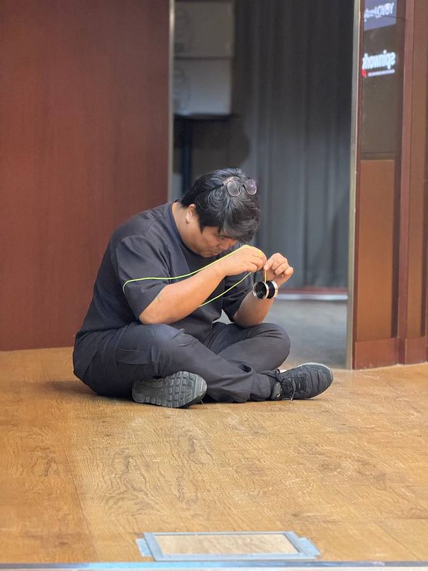 A person is sitting on the floor, focused on a task involving a pair of sunglasses.