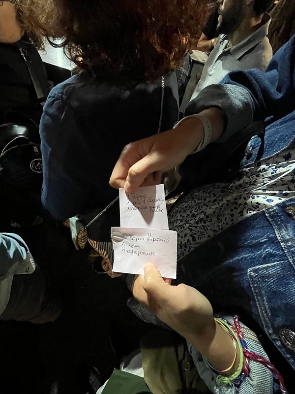 A person holds two handwritten notes while surrounded by a crowd at an event.
