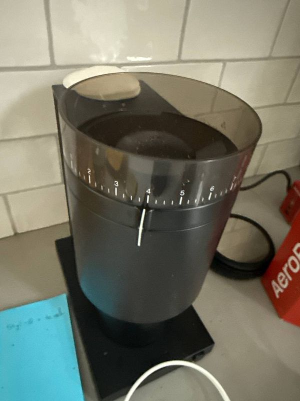 A Fellow Opus coffee grinder is prominently displayed on a countertop.