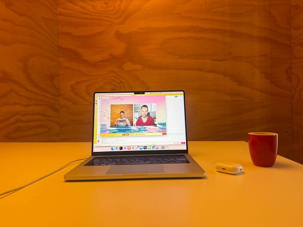 Photograph of a modern home office setup with multiple screens and a laptop on a wooden desk.