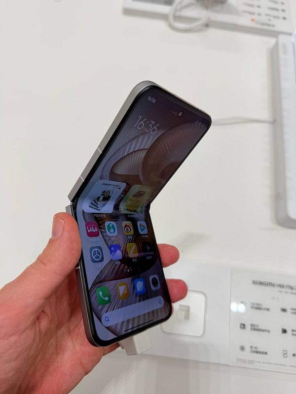 Front and back views of a Xiaomi foldable smartphone with a screen protector and charger.