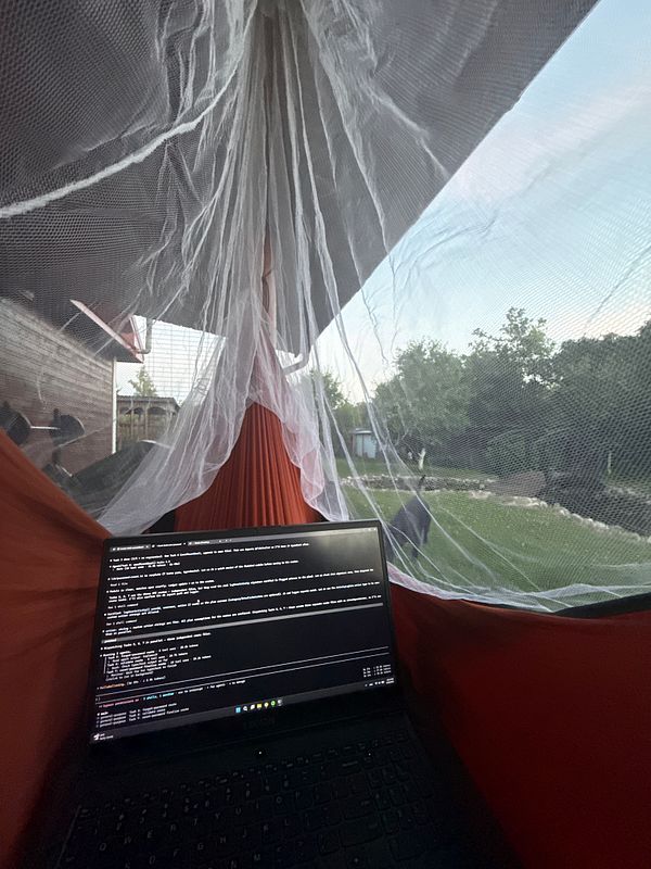 A cozy indoor setup features a draped mosquito net tent with hanging fairy lights and candles creating a warm ambiance in a softly lit room.