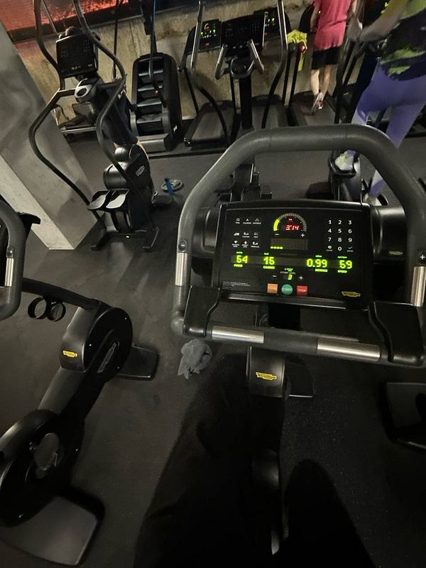 The image captures a gym environment featuring exercise equipment and individuals engaged in workouts.
