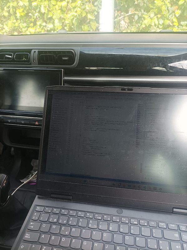 A laptop displaying code is positioned inside a car's interior.