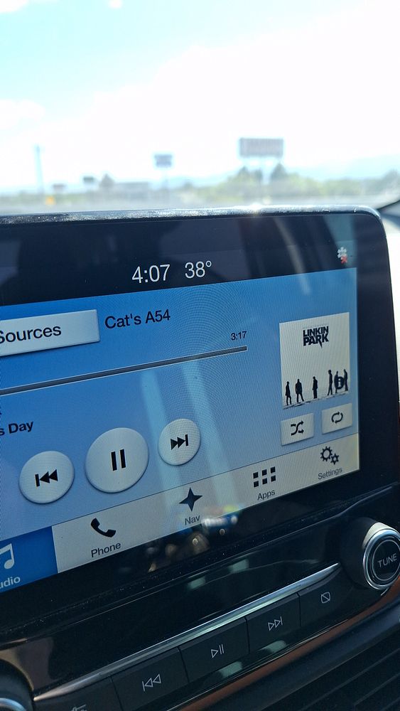 The image captures a car's infotainment screen displaying the current temperature and music information.