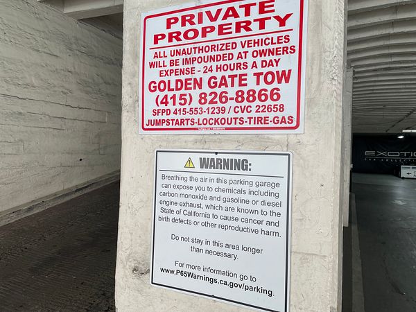 A warning sign in a parking garage highlights health risks associated with air quality.