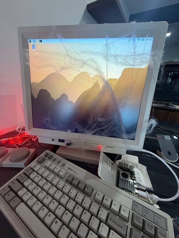 A vintage computer setup featuring a monitor with a Raspberry Pi 5 GUI, surrounded by cobwebs.