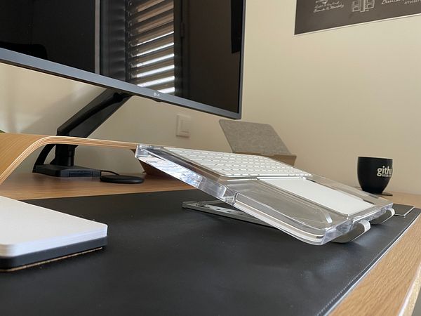 A workspace featuring a tilted keyboard and trackpad tray for ergonomic comfort.