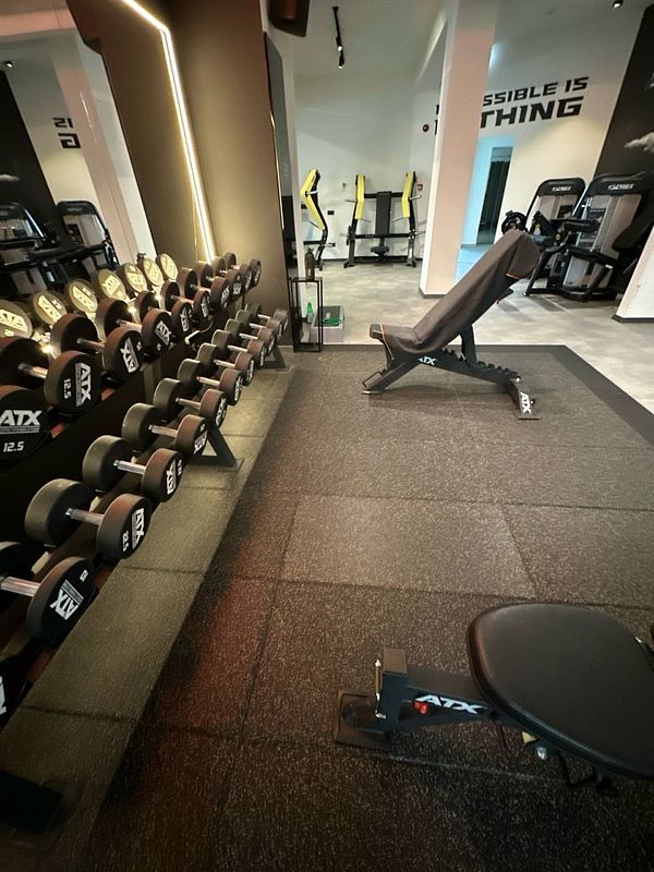 A modern gym space featuring dumbbells, a bench, and various workout equipment.