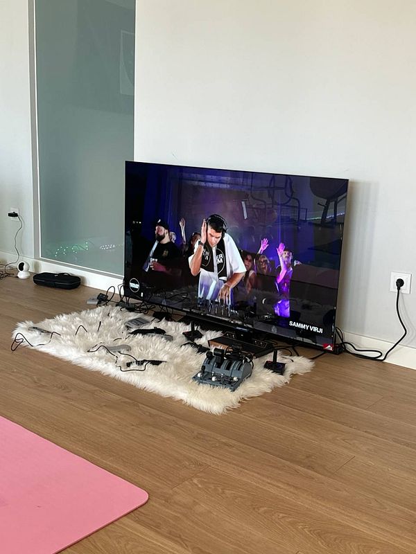 A living room scene featuring a DJ performance on a television screen.