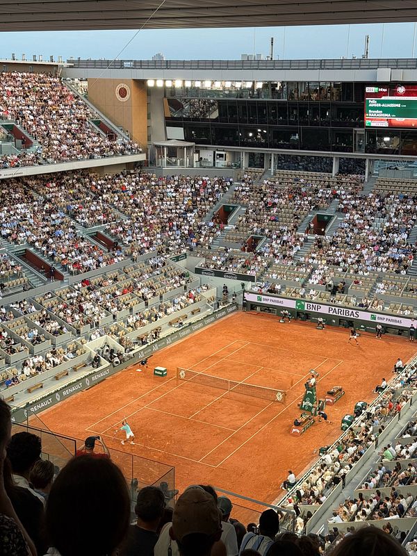 A photo of a large tennis stadium filled with spectators during a tennis match at Roland Garros.