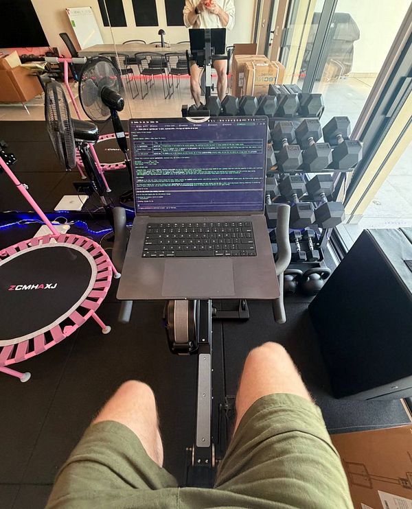 Photograph of a person jogging on a paved path surrounded by green grass under a clear sky.