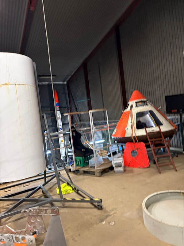 The image captures a section of a rocket lab featuring various rocket components and equipment.