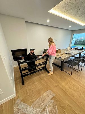 A man and a woman are assembling gym equipment in a modern living space.