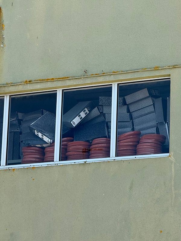 The image captures a window filled with stacked boxes and circular containers.