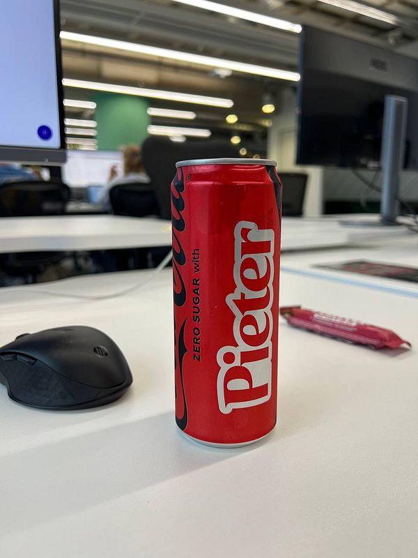A can of Pieter juice is prominently displayed on a desk in an office environment.