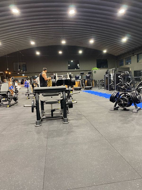 A spacious gym interior featuring various workout equipment and individuals exercising.