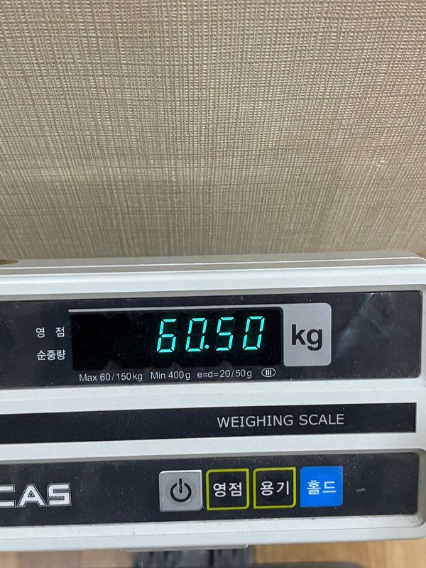 A digital weighing scale displays a weight of 60.50 kg.