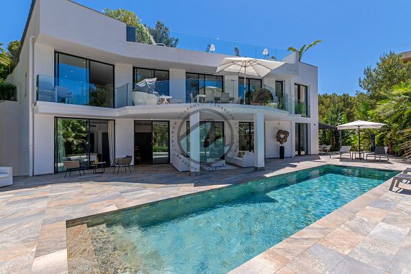 A modern villa with a swimming pool and outdoor seating area surrounded by lush greenery.