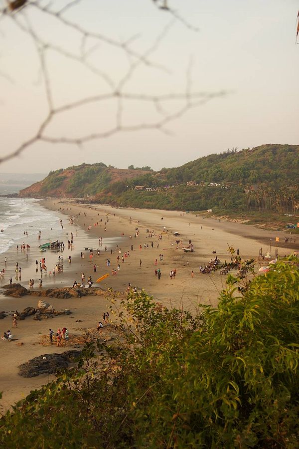 A scenic view of a beach in Goa filled with people enjoying the sunset.