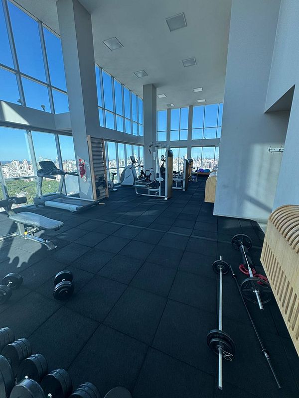 A spacious gym with large windows and various workout equipment.