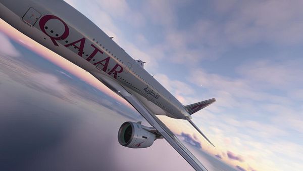 A Qatar Airways airplane is flying through a colorful sky during sunset.