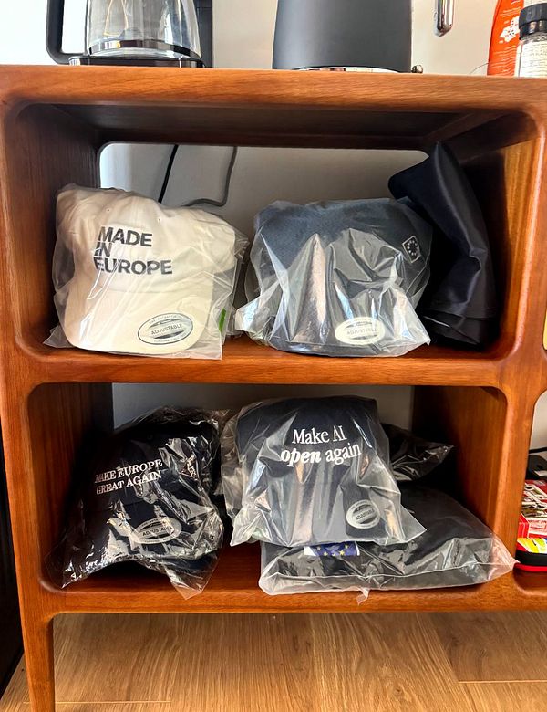 A wooden shelf displays various hats and shirts, all packaged in plastic.